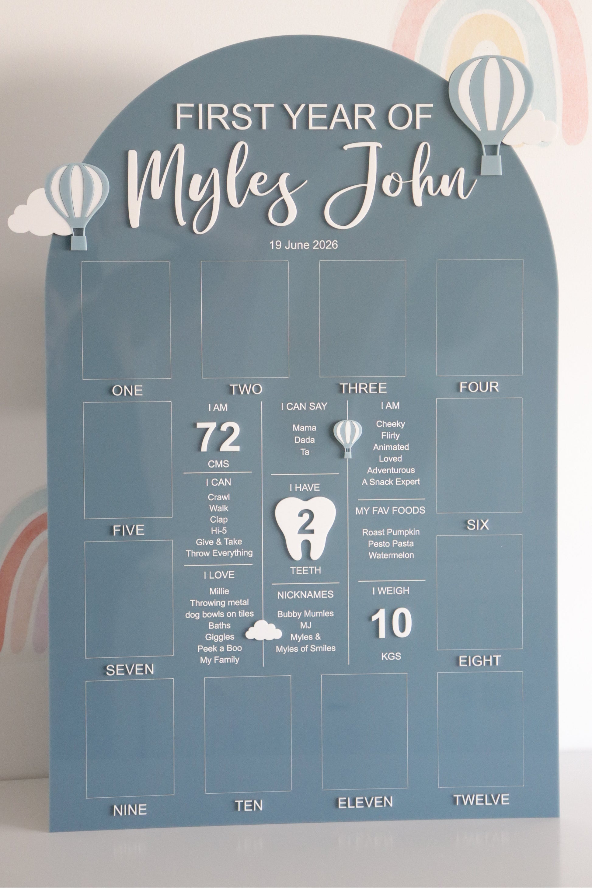 Baby milestone chart with text 'First Year of' on a blue background with hot air balloon and clouds