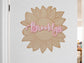A personalized sunflower wall decal with the name 'Brooklyn' in pink script, displayed on a white door in an indoor room setting.